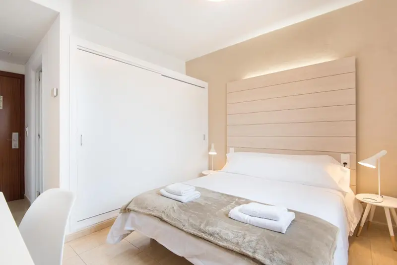 Une chambre lumineuse avec un grand lit et une armoire.