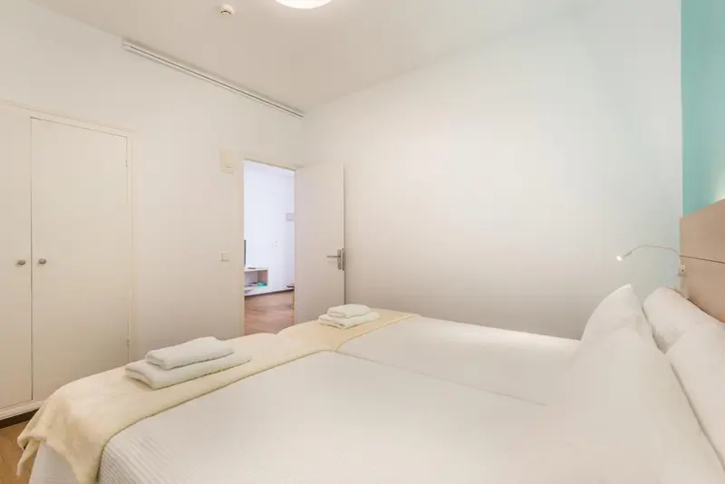 Une chambre lumineuse avec un lit double et une armoire.