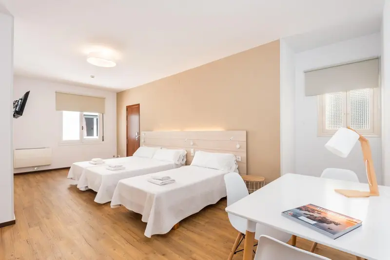 Chambre lumineuse avec deux lits simples et un bureau.