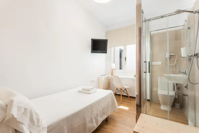 Une chambre lumineuse avec un lit simple et une salle de bain attenante.