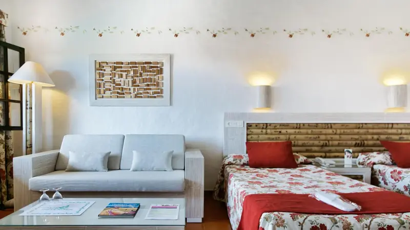 Une chambre lumineuse avec un canapé et un lit décoré de coussins.