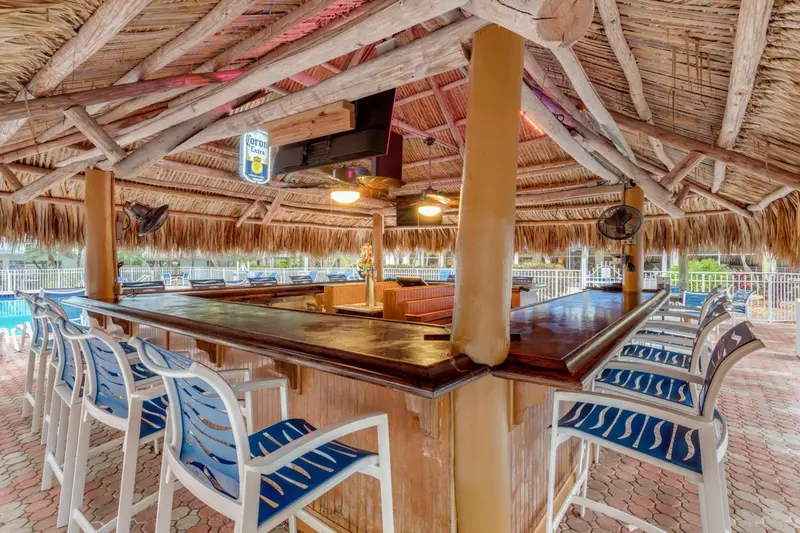 Un bar en plein air avec des tabourets et un comptoir en bois.