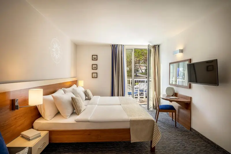 Une chambre lumineuse avec un grand lit et un accès à un balcon.