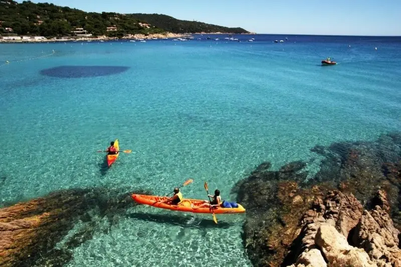 Des kayaks naviguent sur une eau turquoise claire près d'une côte rocheuse.