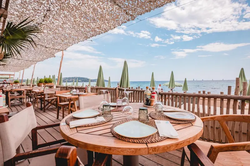Tables dressées en terrasse avec vue sur la mer et le ciel nuageux.