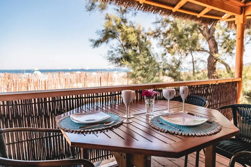 Une table dressée pour deux sur une terrasse en bois avec vue sur la mer.