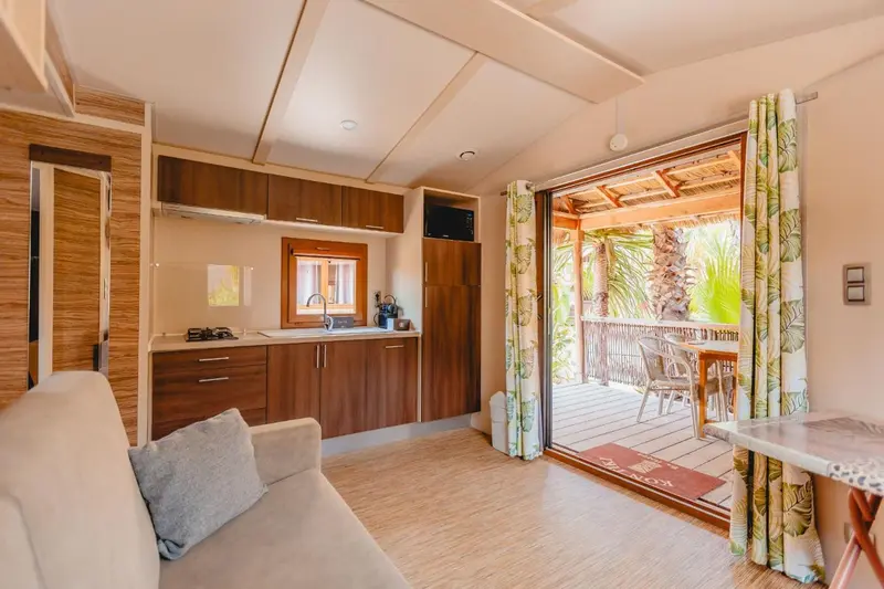 Interieur lumineux avec cuisine et espace repas ouvert sur une terrasse.
