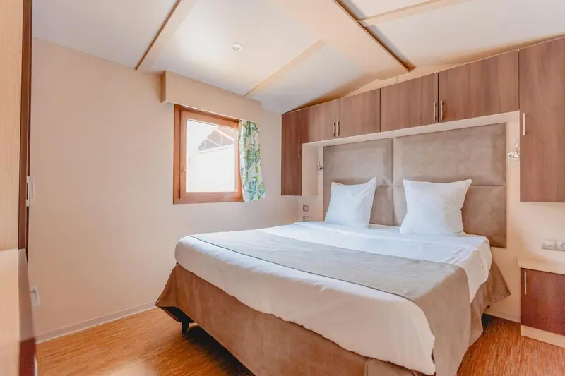 Une chambre lumineuse avec un grand lit et des rangements muraux.