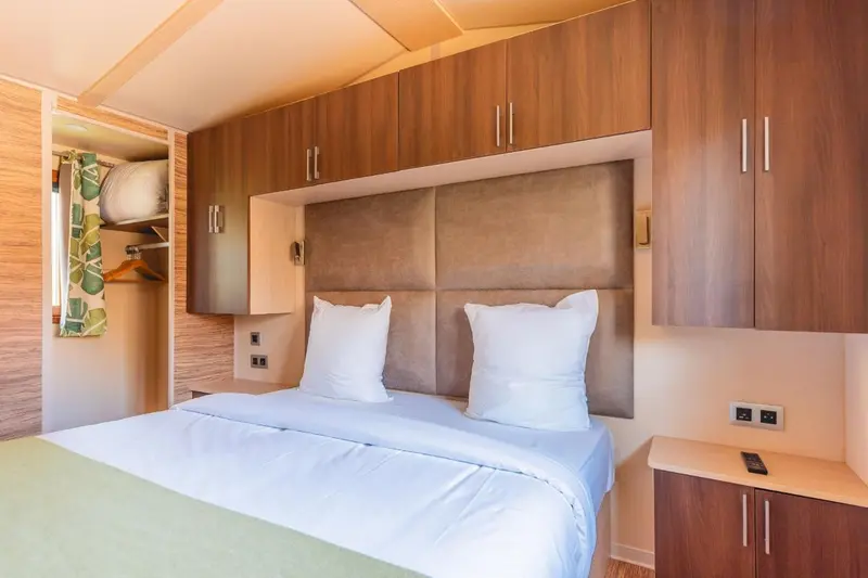 Une chambre avec un grand lit et des rangements muraux.