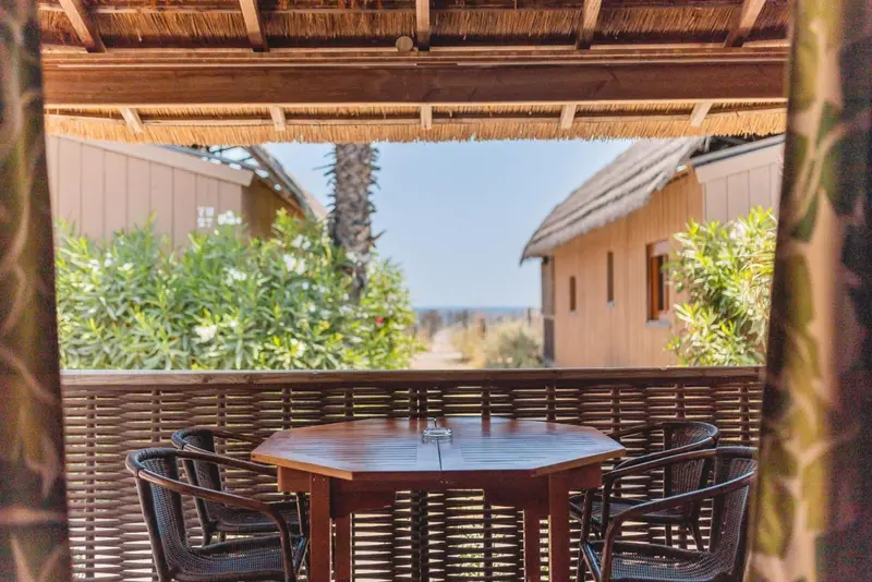 Une table ronde et des chaises se trouvent sur une terrasse ombragée.