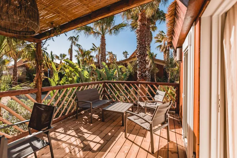 Terrasse en bois avec mobilier d'extérieur et végétation luxuriante.