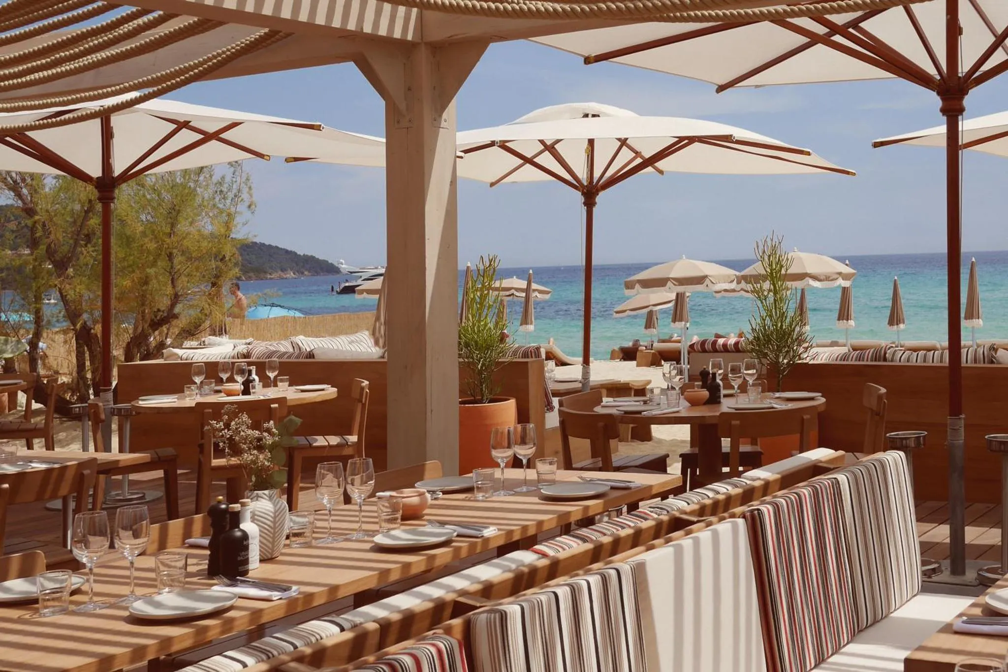 Tables dressées sur une terrasse ombragée avec vue sur la mer.