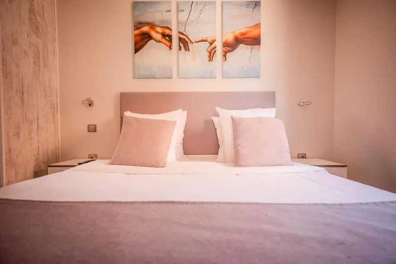 Une chambre avec un grand lit et des tableaux décoratifs au mur.