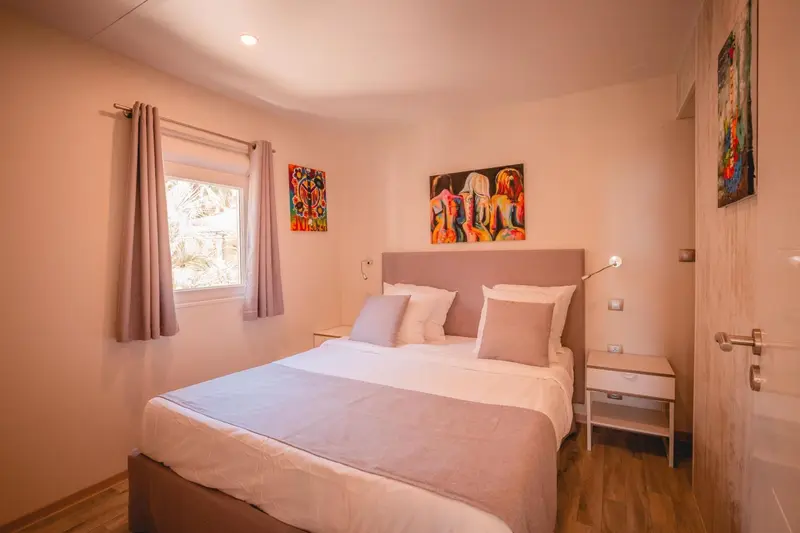 Une chambre lumineuse avec un grand lit et des tableaux colorés.