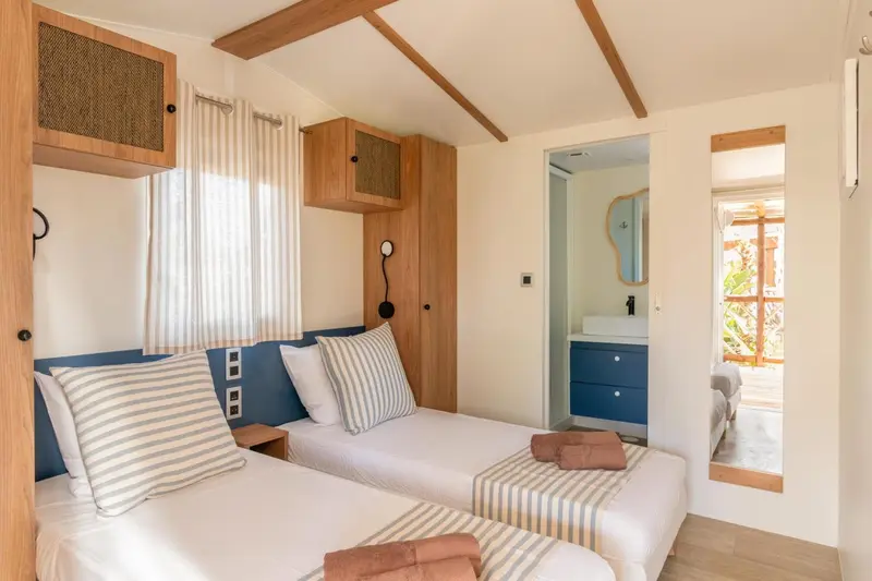 Une chambre lumineuse avec deux lits simples et une décoration sobre.