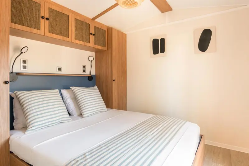 Une chambre lumineuse avec un lit double et des rangements muraux.