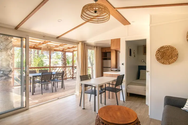 Espace de vie lumineux avec coin repas et terrasse en bois.