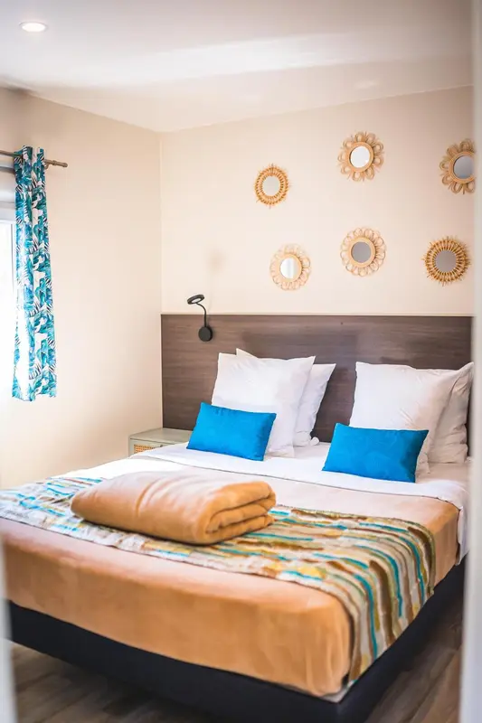 Une chambre avec un grand lit recouvert d'une courtepointe colorée et décorée de coussins.