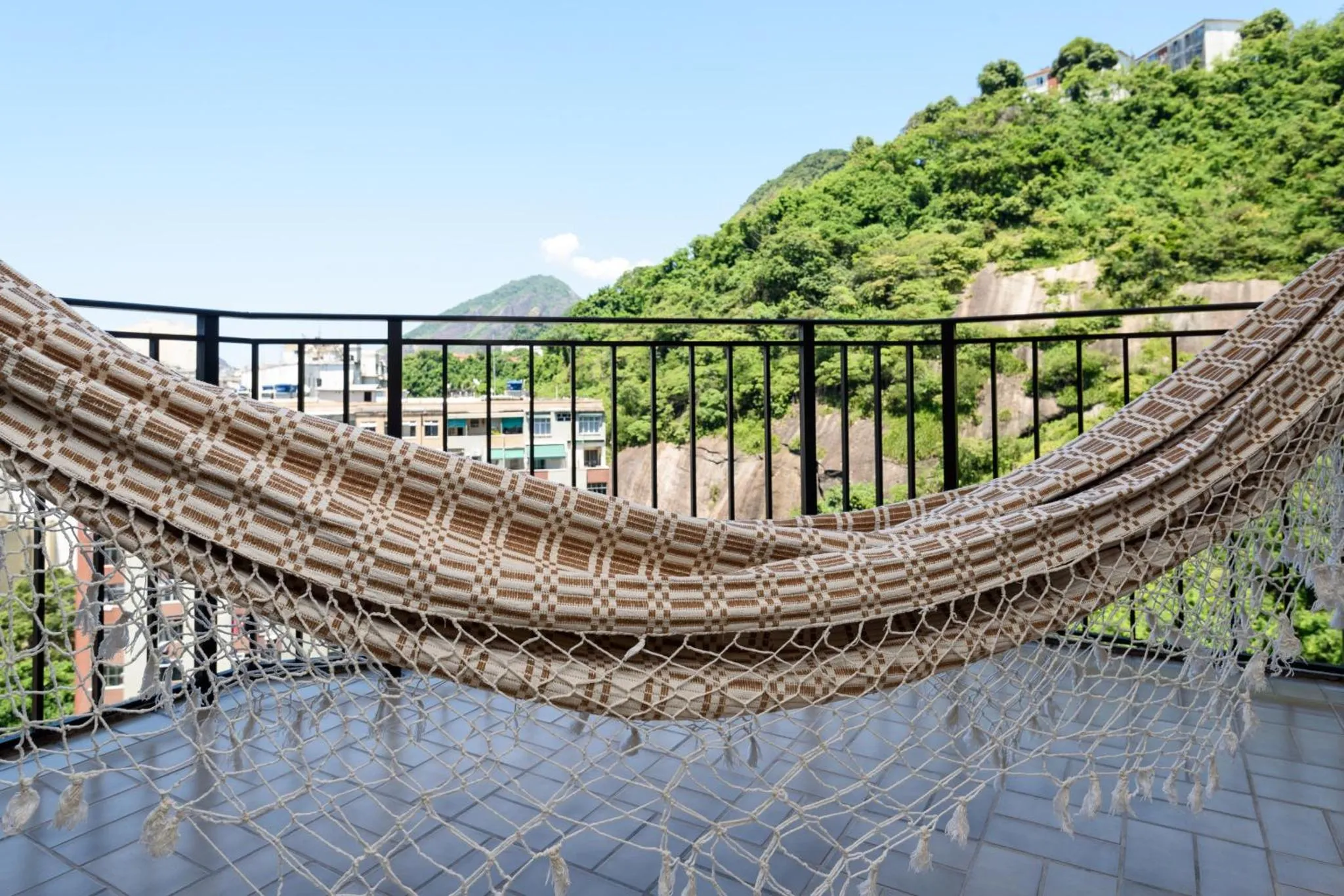 Un hamac suspendu sur une terrasse avec vue sur la végétation.