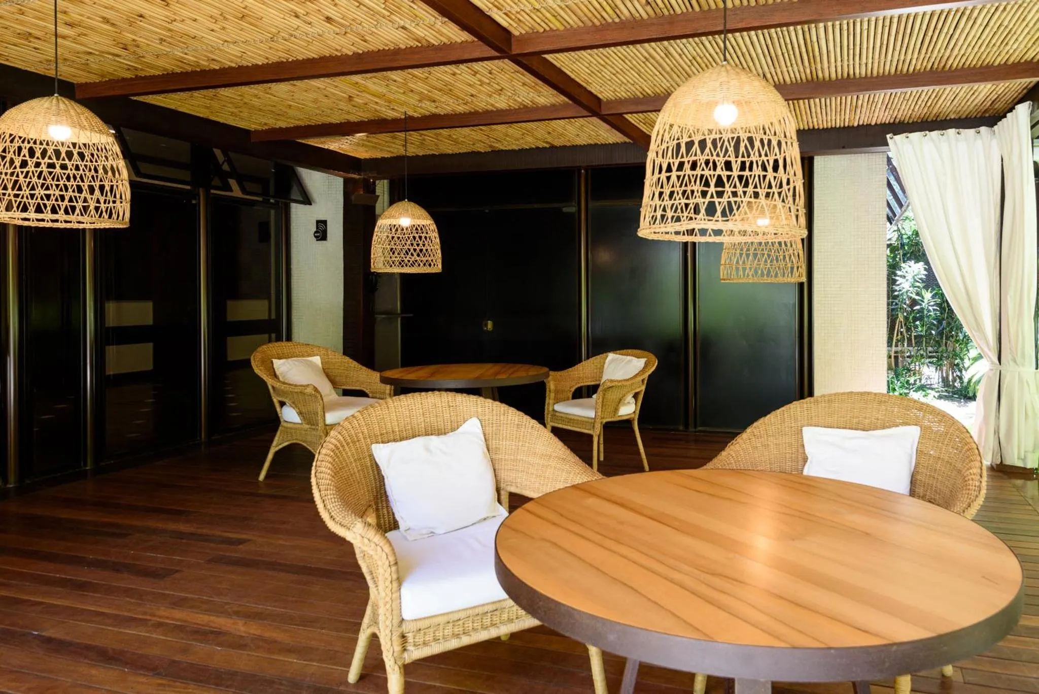 Espace de détente extérieur avec mobilier en rotin et éclairage suspendu.