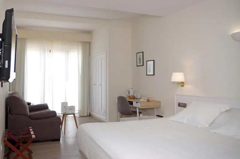 Une chambre lumineuse avec un lit fait et un coin salon.
