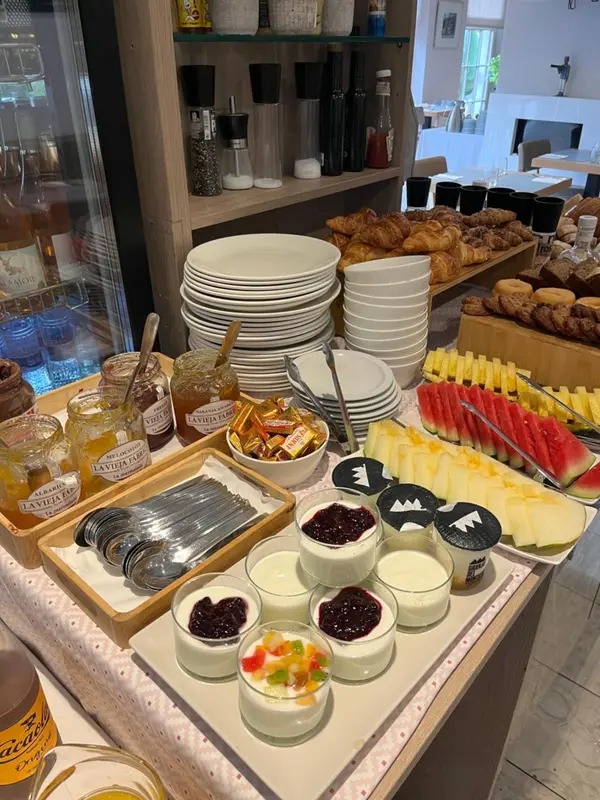 Un buffet propose des viennoiseries, des confitures, des fruits et des céréales.