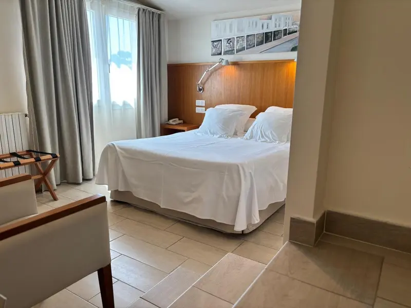 Une chambre lumineuse avec un grand lit recouvert de draps blancs.