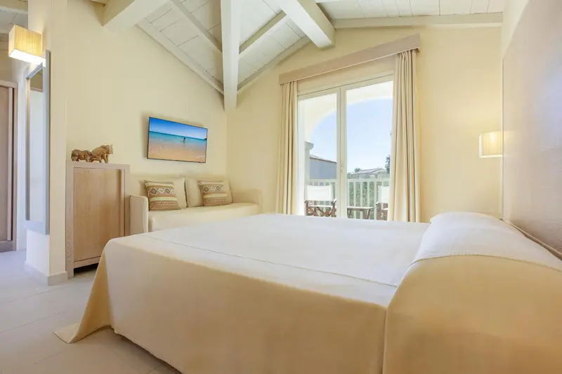 Une chambre lumineuse avec un grand lit et un canapé près d'une baie vitrée.