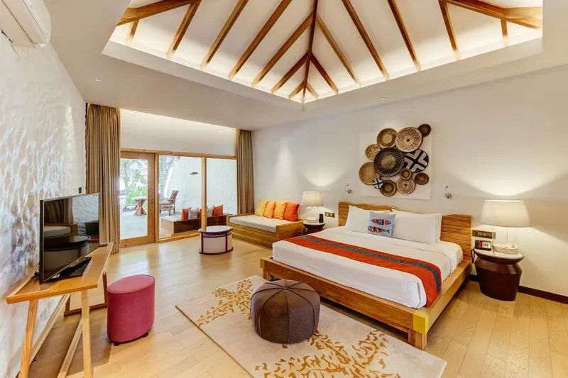 Une chambre lumineuse avec un grand lit et un espace salon.