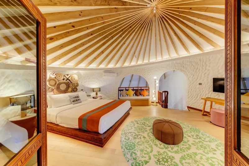 Chambre à coucher lumineuse avec un lit à baldaquin et un décor tropical.