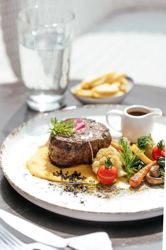 Assiette de viande grillée accompagnée de légumes et de frites.