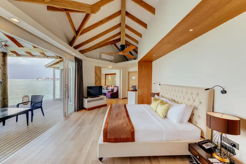 Une chambre lumineuse avec un lit king-size et un accès direct à une terrasse en bois.