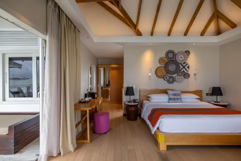 Une chambre lumineuse avec un lit double et un bureau près d'une fenêtre.