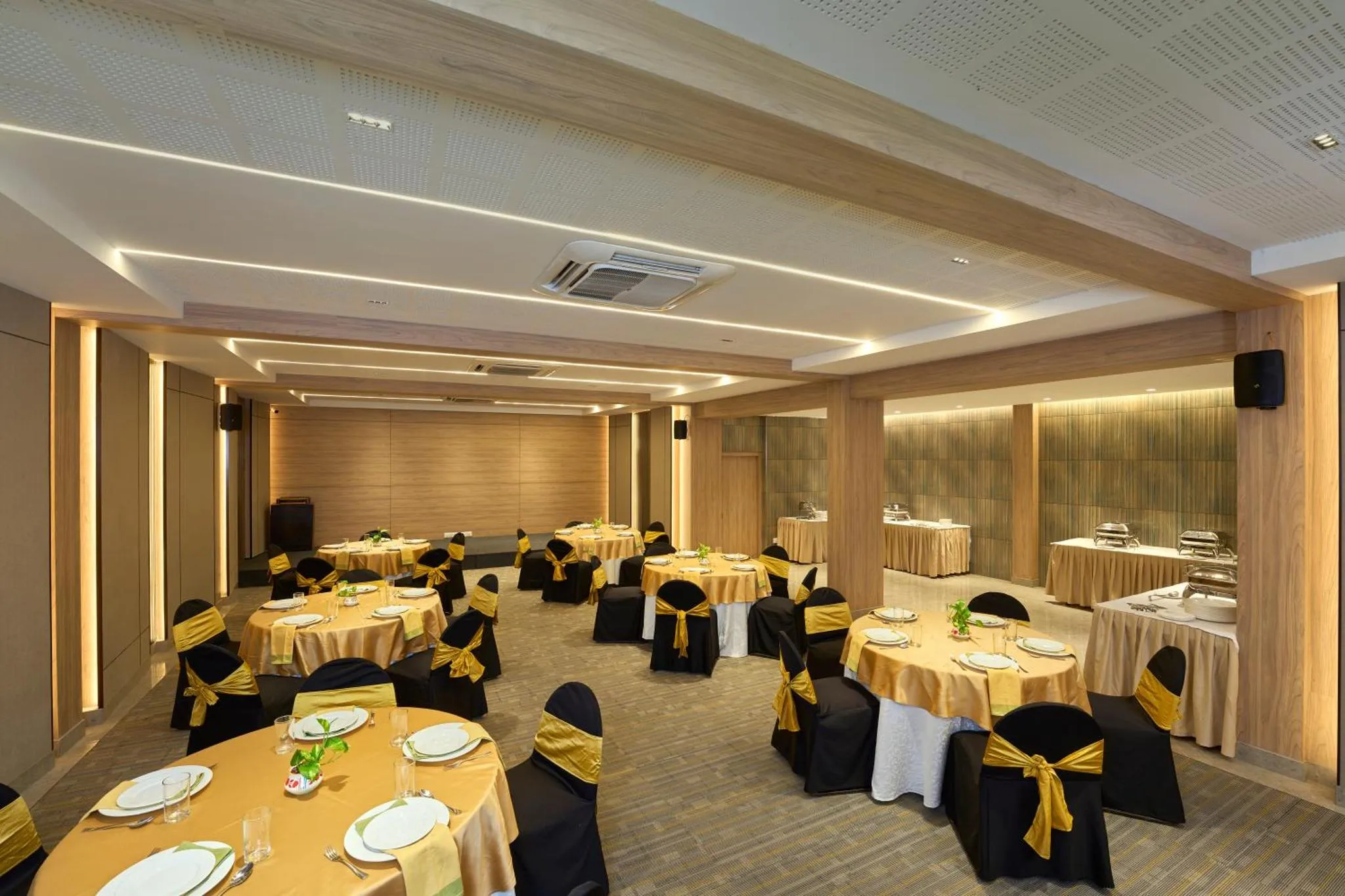 Une salle lumineuse est aménagée avec des tables rondes dressées pour un repas.
