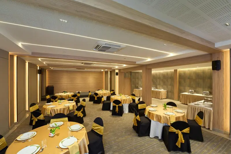 Une salle lumineuse est aménagée avec des tables rondes dressées pour un repas.