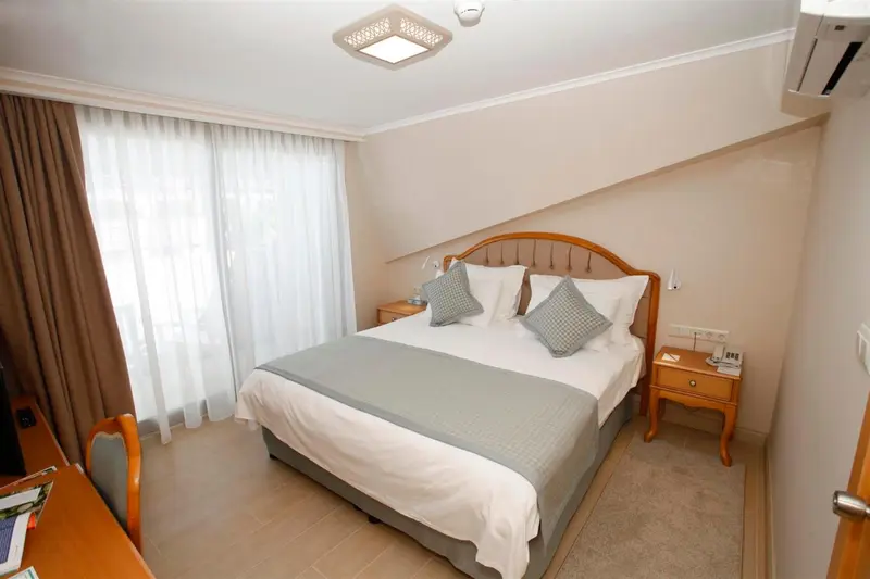 Une chambre d'hôtel lumineuse avec un lit double et des tables de chevet.