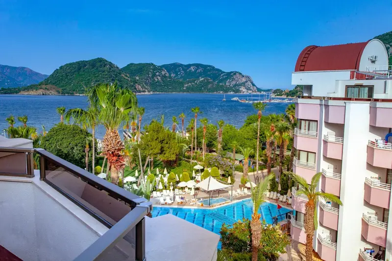 Vue aérienne d'un complexe hôtelier avec piscine et végétation luxuriante face à la mer.