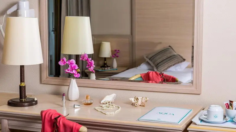 Une coiffeuse avec un miroir et des objets personnels est mise en scène dans une chambre.