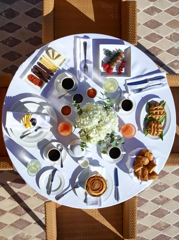 Table ronde dressée avec un copieux petit-déjeuner.