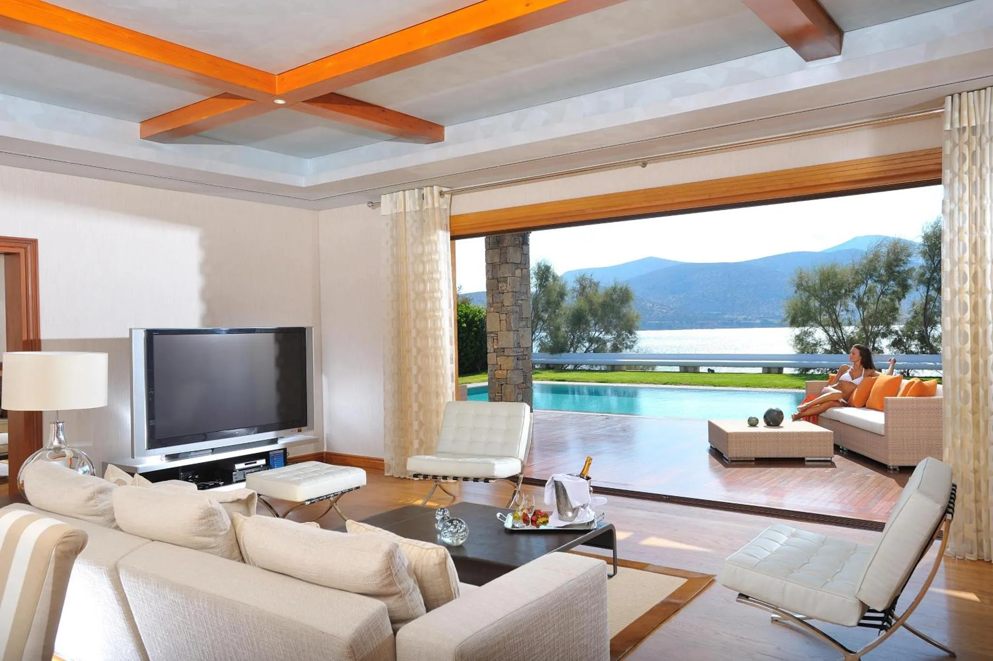 Un salon lumineux s'ouvre sur une terrasse avec vue sur la mer et une piscine.
