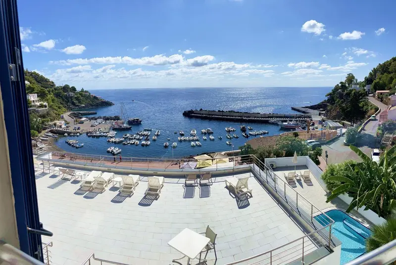 Vue d'une baie ensoleillée depuis une terrasse avec transats et piscine.