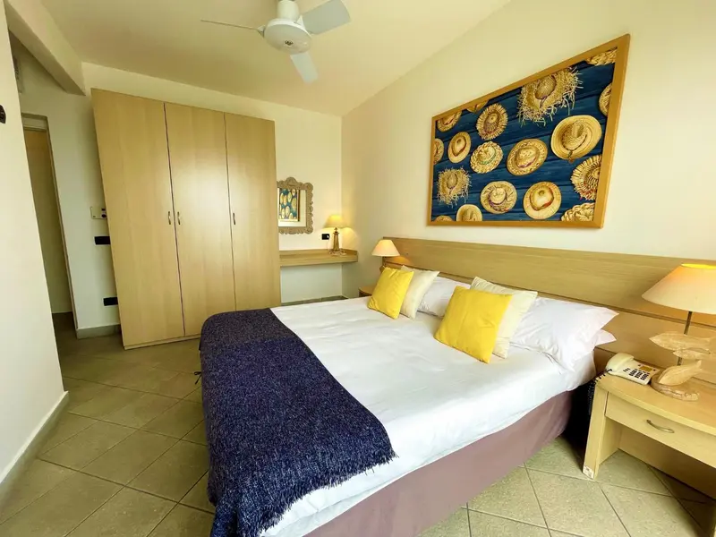 Une chambre lumineuse avec un grand lit recouvert d'une couverture bleue et de coussins jaunes.