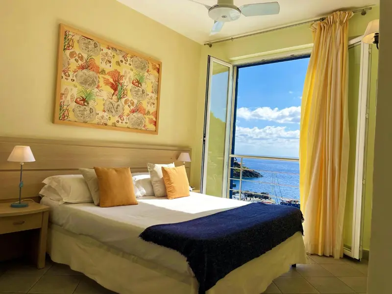 Une chambre lumineuse avec un grand lit donnant sur une vue mer.