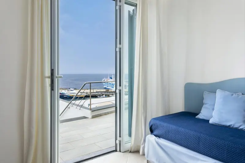 Une chambre lumineuse s'ouvre sur une vue mer à travers de larges baies vitrées.