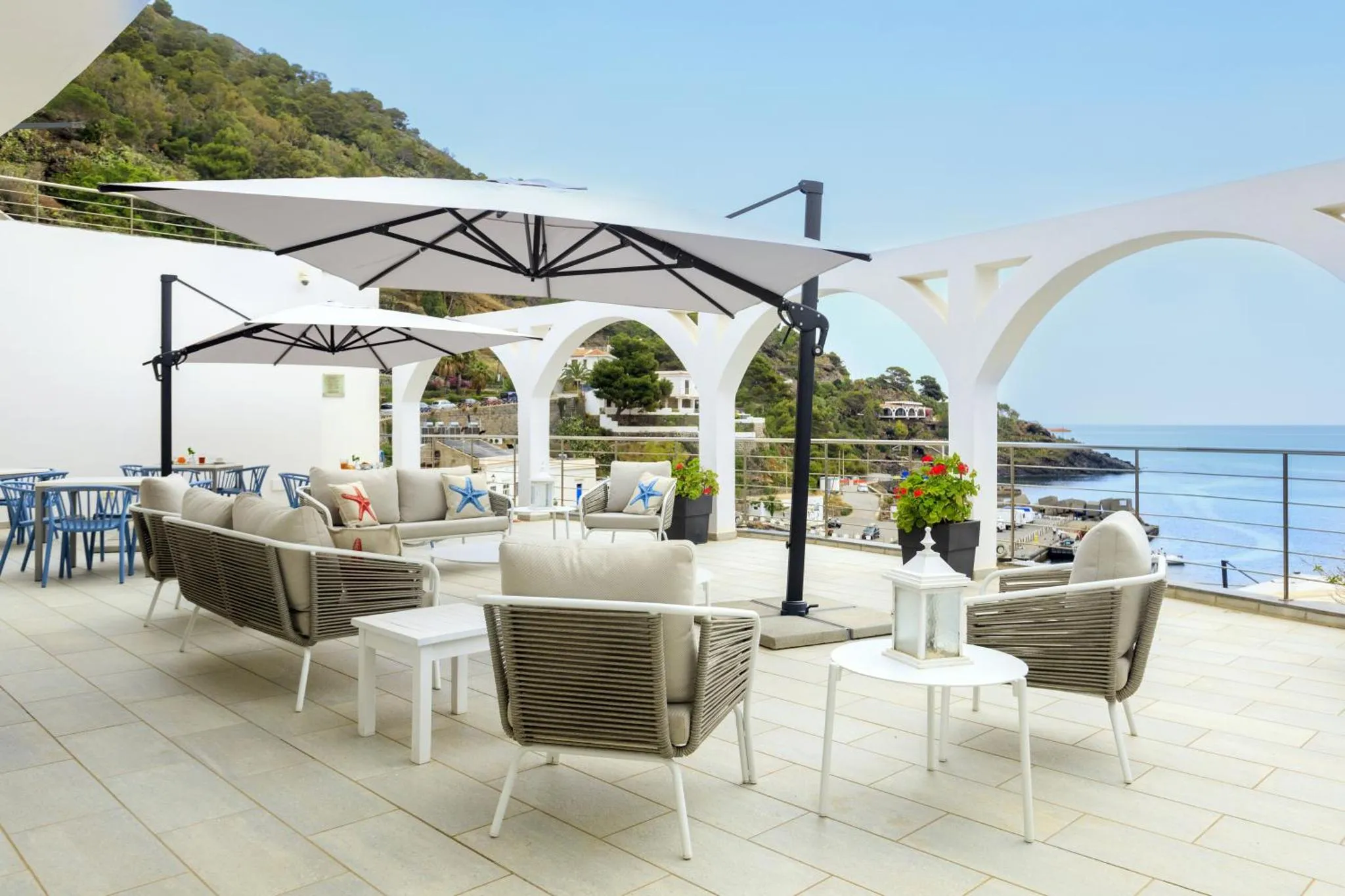 Espace de détente extérieur avec mobilier de jardin et vue sur la mer.