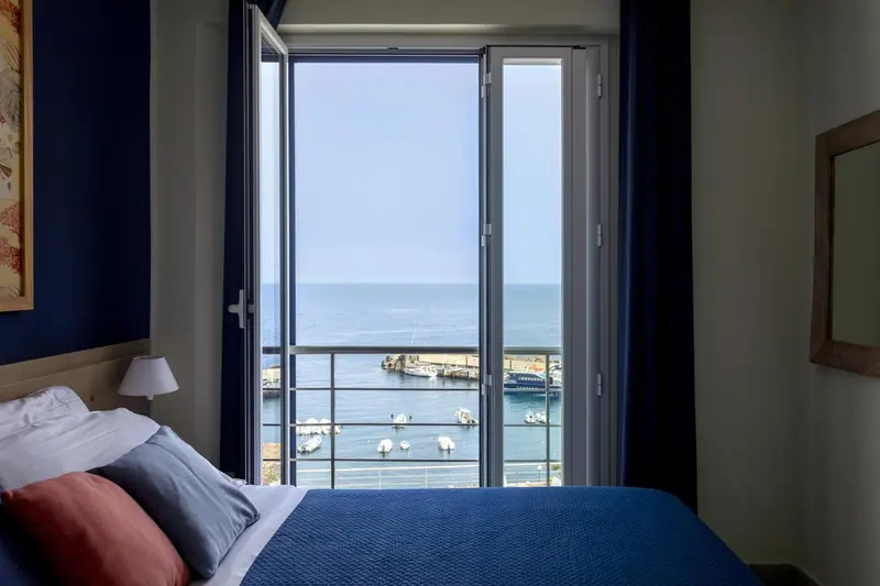 Une chambre avec vue sur la mer depuis un balcon.
