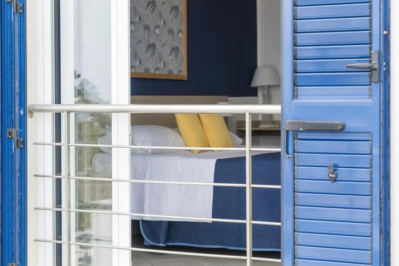Une chambre lumineuse s'ouvre sur un balcon bleu.