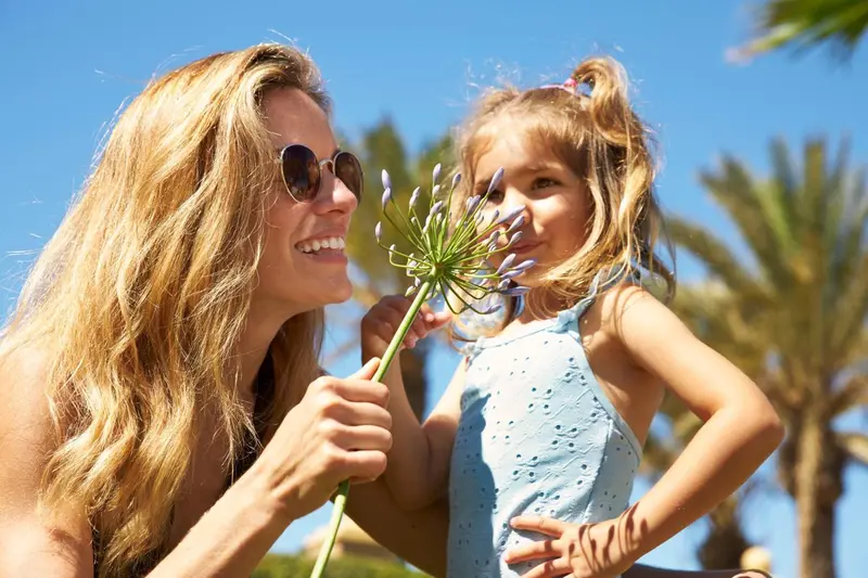 Une femme et une enfant sourient en tenant une fleur.