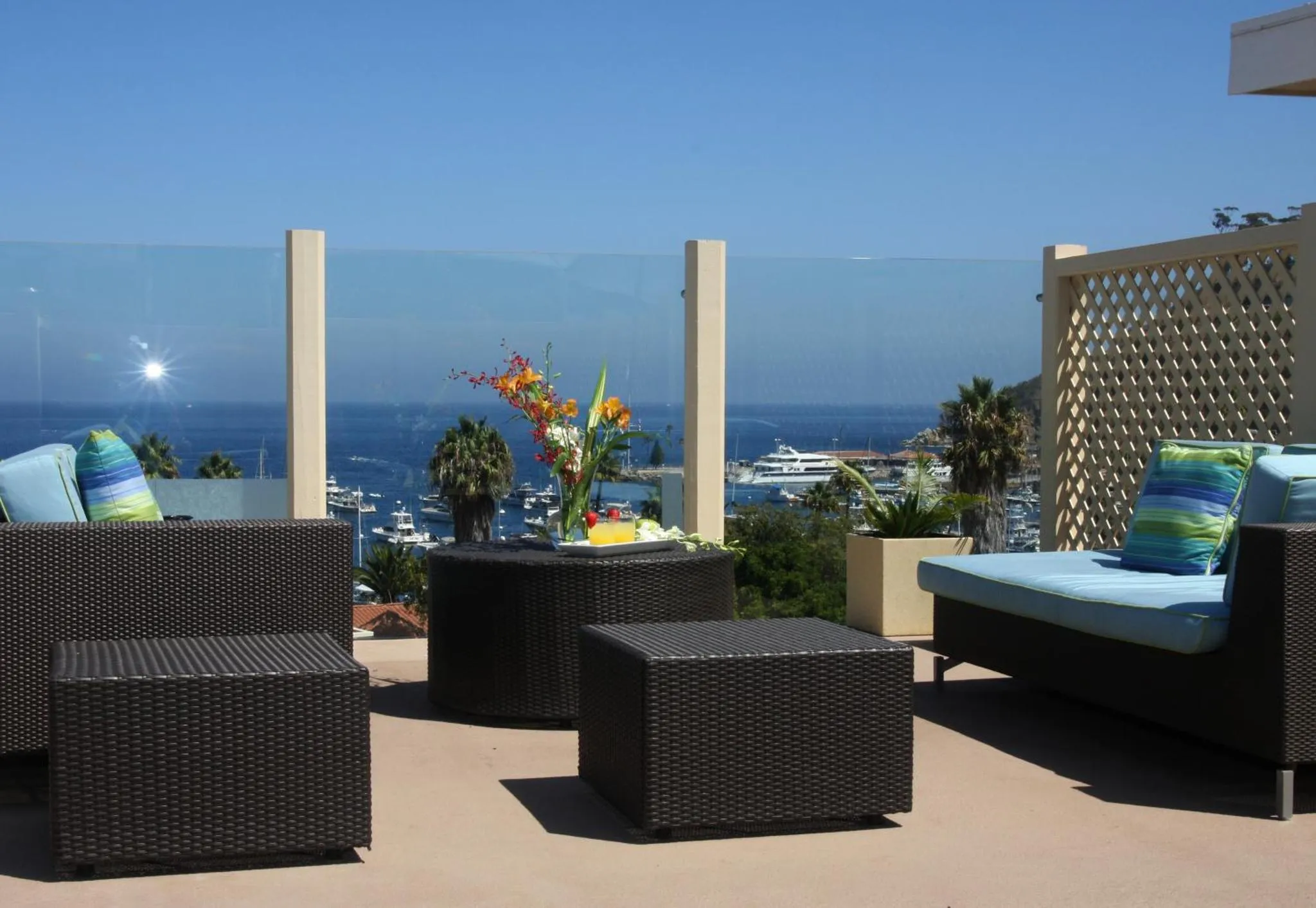 Espace de détente extérieur avec mobilier en rotin et vue sur la mer.