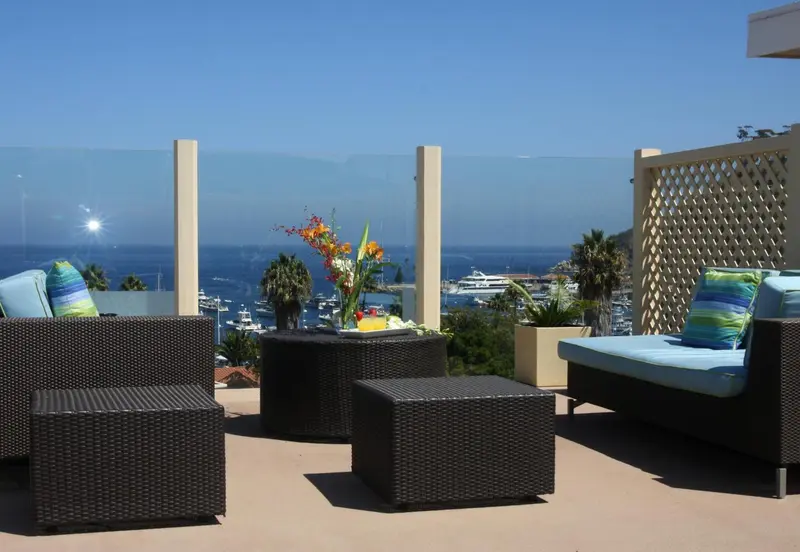 Espace de détente extérieur avec mobilier en rotin et vue sur la mer.